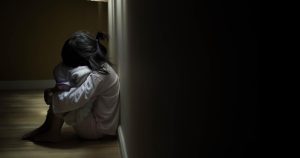 Squat single child sit near window, sad lonely in dark night ind